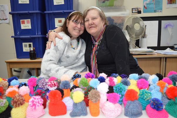 Two ladies from the Guildford Knit and Natter group sat at a table with al 95 woollen hats