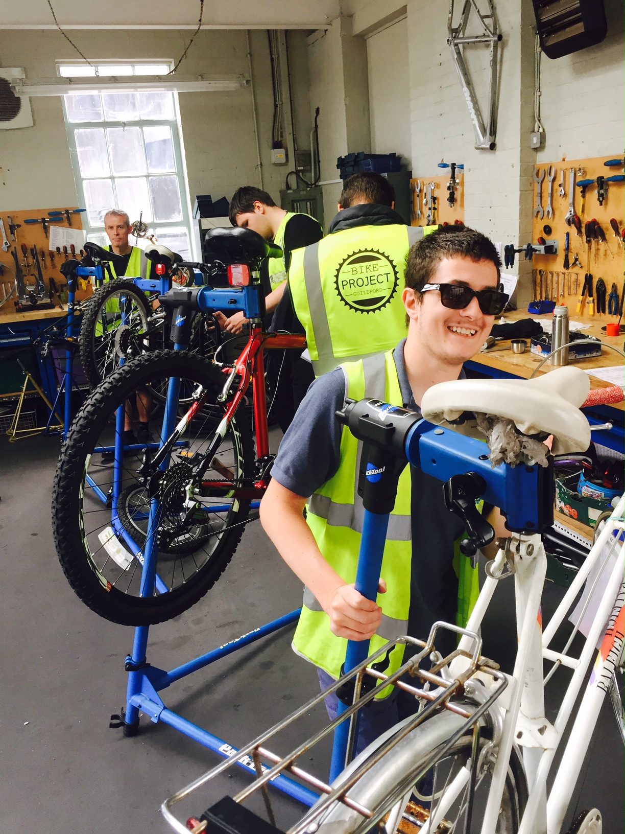 Three bike project students maintaining bicycles in the workshop