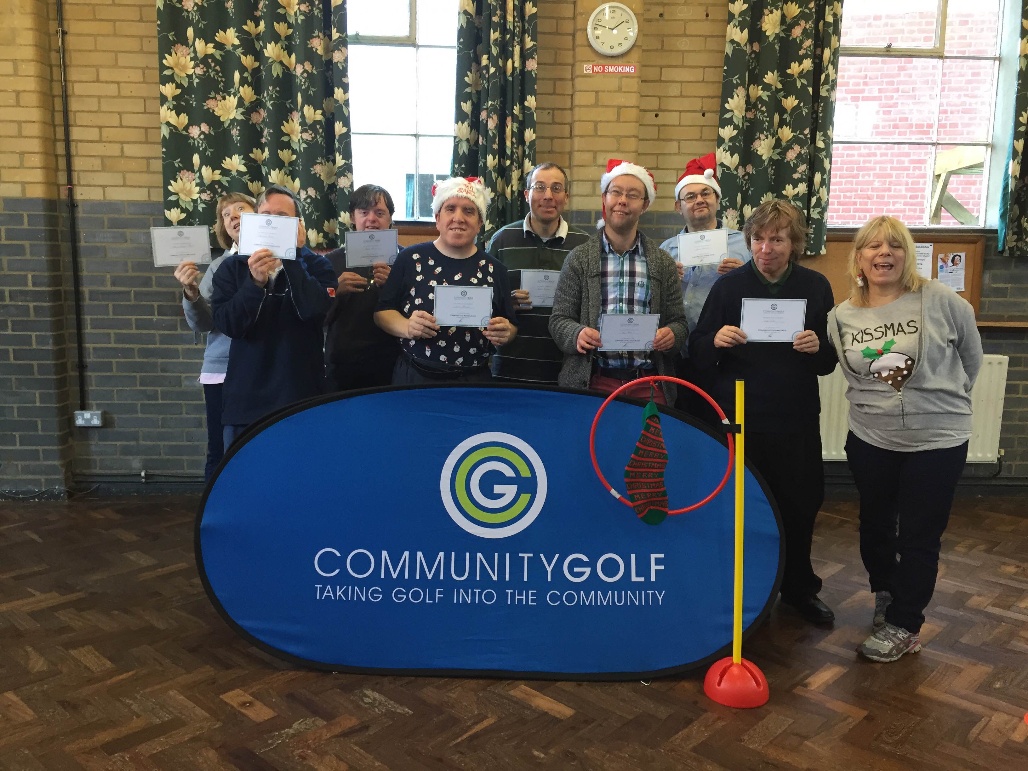 A group of customers all wearing Christmas hats or jumpers holding their Community Golf certificates